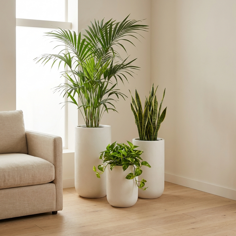 Matched set of three graduated fiberglass cylinder planters in limestone white in an architectural living room