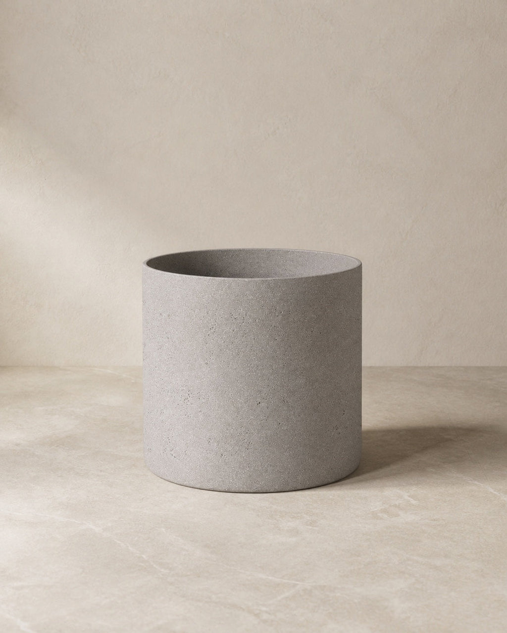 Angled view of the Cement Grey Agnes Planter on a warm-neutral limestone floor.