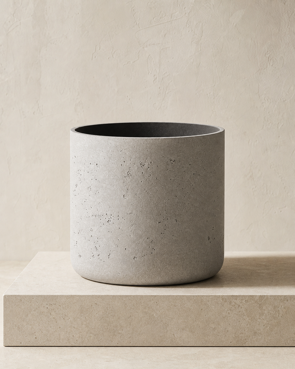 Agnes cement-grey cylindrical planter on a limestone plinth in warm natural light.