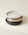 Terra Saucer Collection stack of finish-matched planter saucers in limestone white, bone, and charcoal