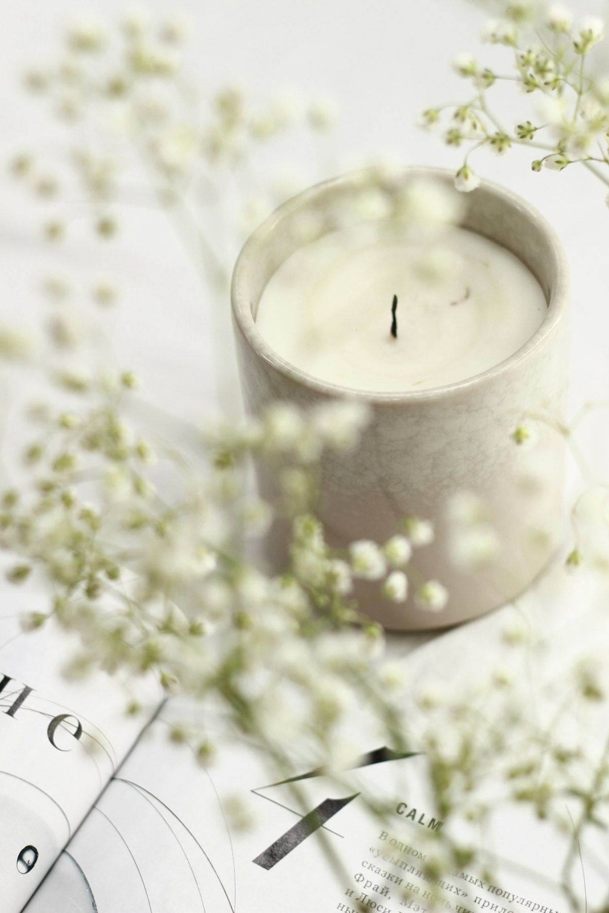 Candle on styled surface with natural materials and soft light