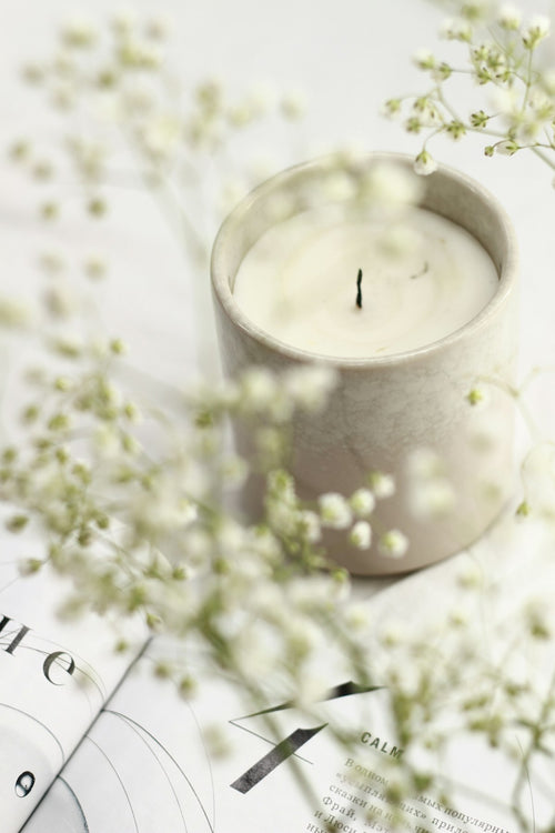 Candle on styled surface with natural materials and soft light