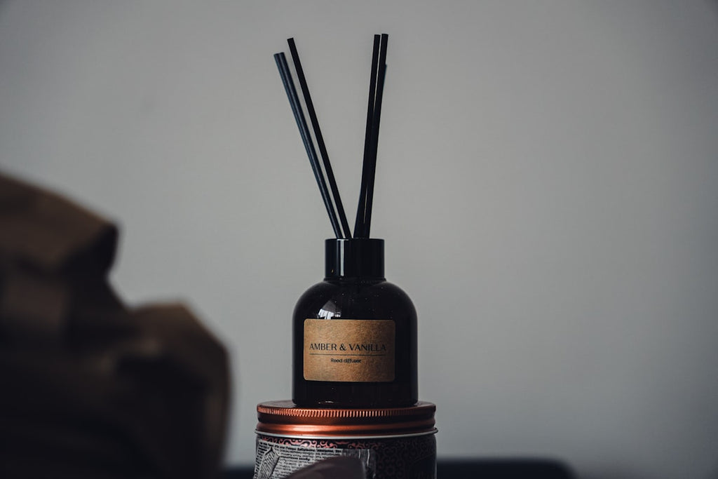 Amber reed diffuser with black reeds on styled shelf