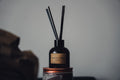 Amber reed diffuser with black reeds on styled shelf