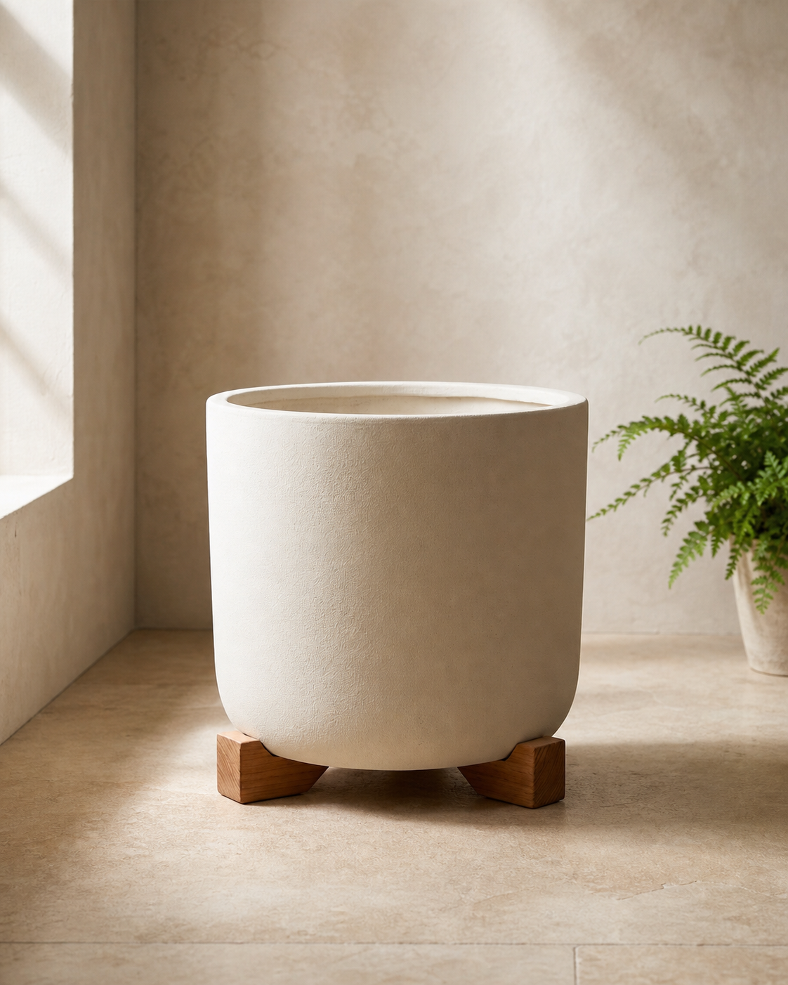 Alder pot feet supporting a warm white round planter on pale limestone.