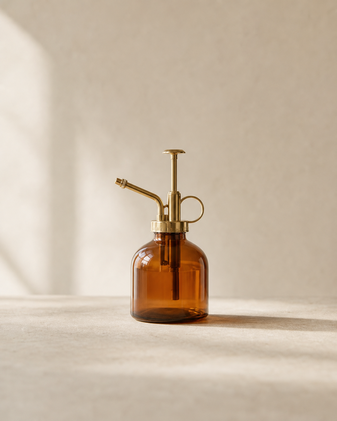 Amber glass mist bottle with brass sprayer on pale limestone.