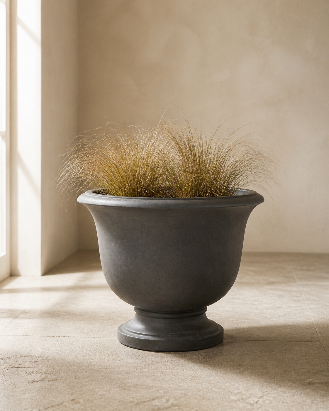 Cairn graphite round pedestal planter with bronze ornamental grasses.