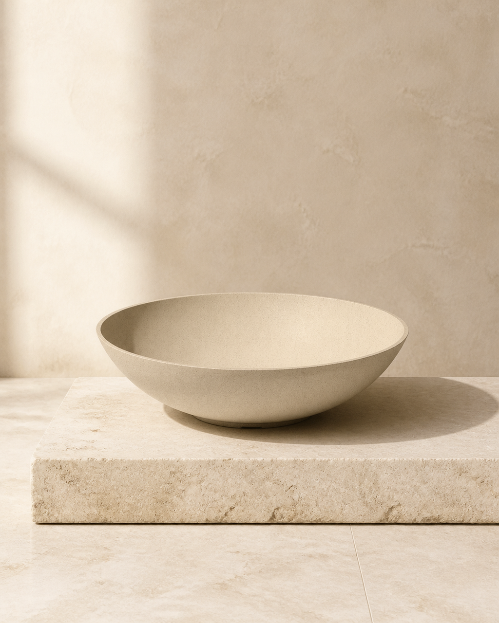 Sand Hevea low bowl planter on a limestone plinth in warm natural light.