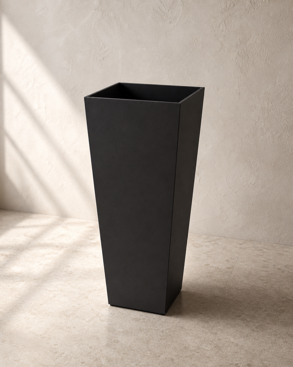 Black tapered tall Hevea outdoor planter against warm limewashed plaster.