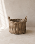 Natural woven handled planter with a clear liner on pale limestone.