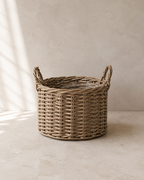 Natural woven handled planter with a clear liner on pale limestone.