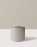 Cylindrical concrete planter on a white surface with a neutral background