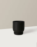 Black ceramic cup on a white surface with a beige background