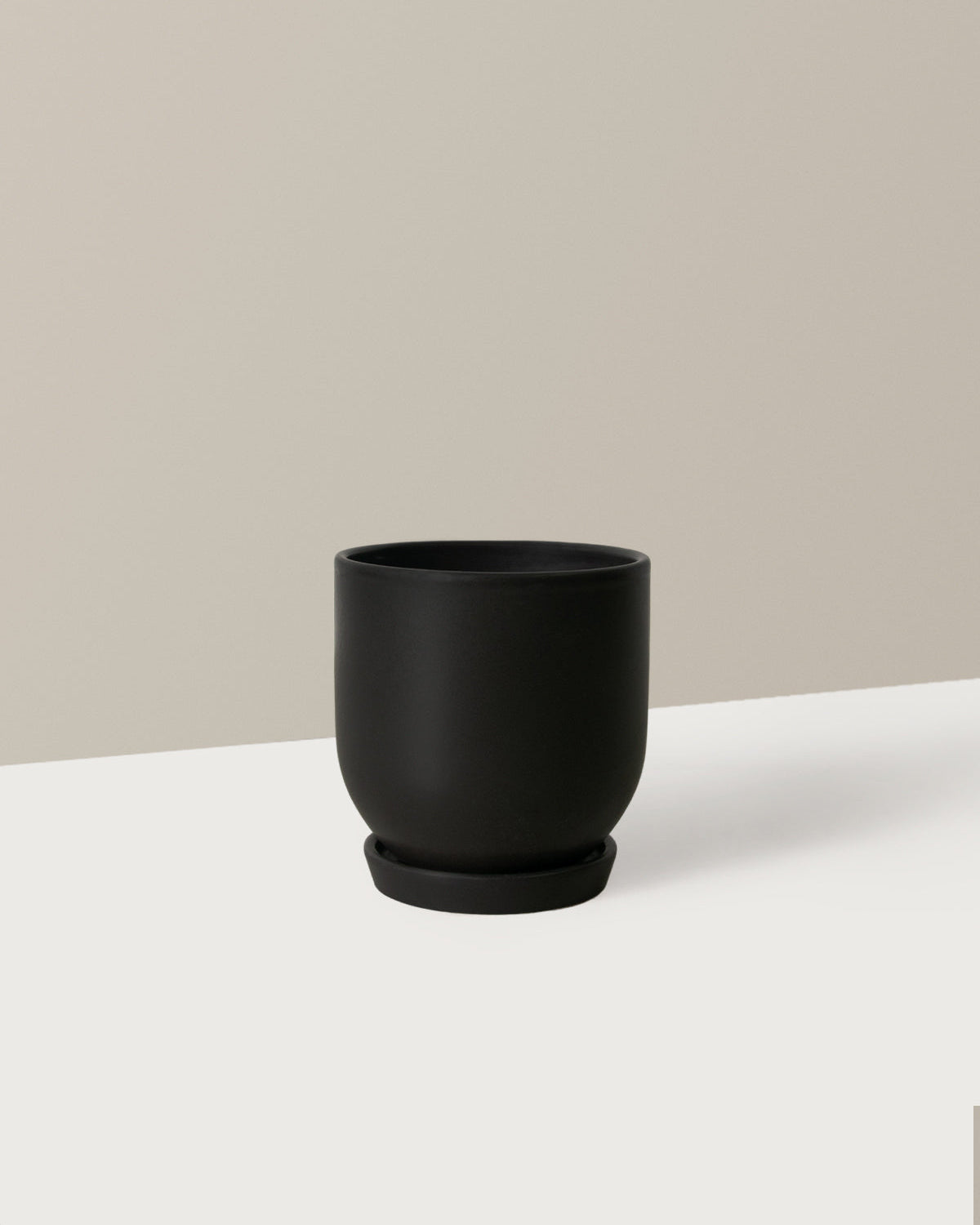 Black ceramic cup on a white surface with a beige background